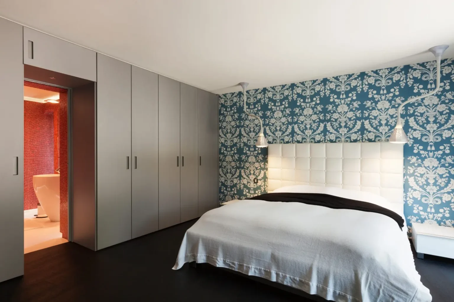 Townhouse bedroom with wall-to-wall fitted wardrobes, a patterned feature wall and an ensuite door