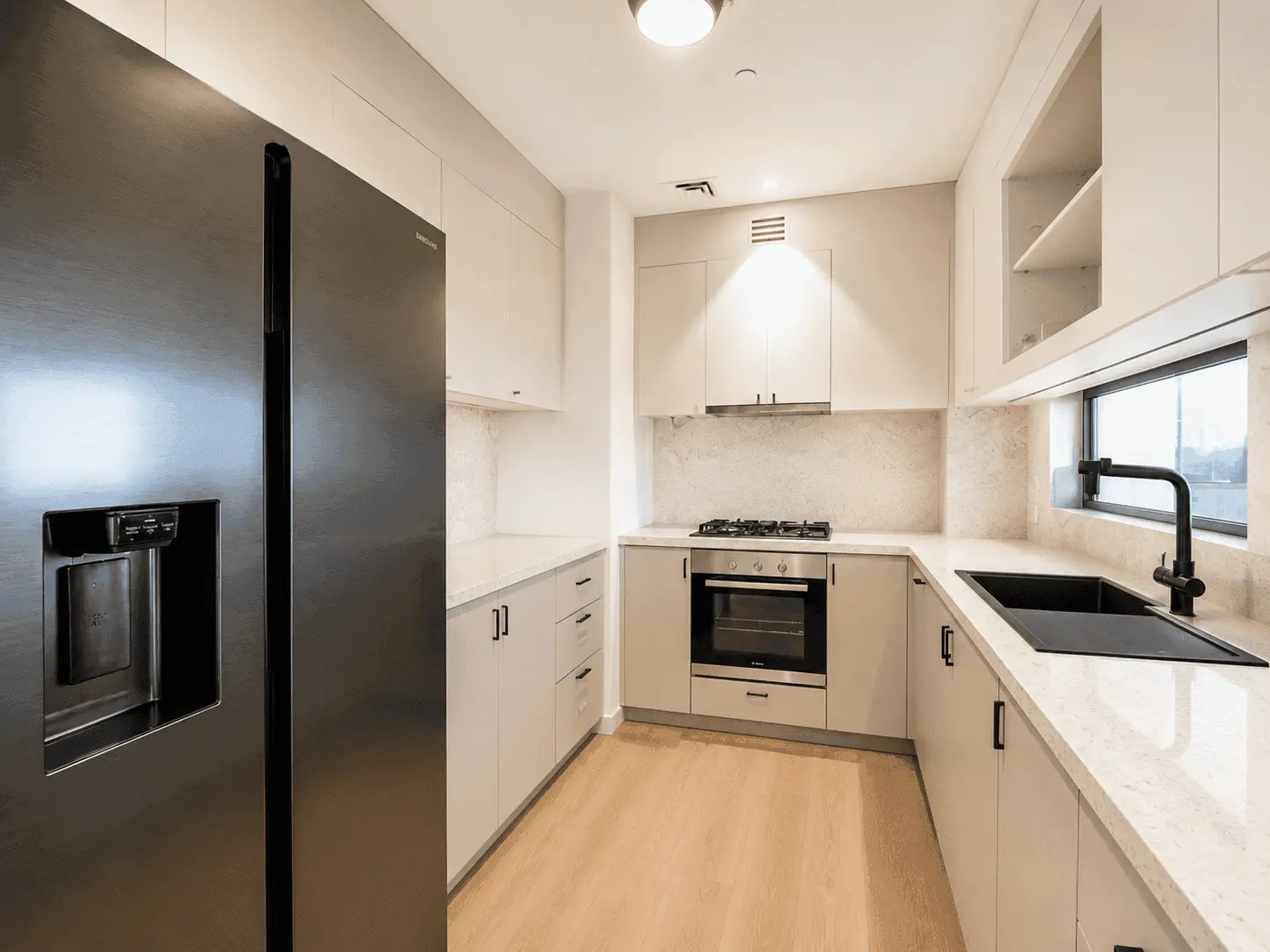 Kitchen renovation in Dubai Hills Estate with greige cabinets, quartz counters, black sink and built-in oven