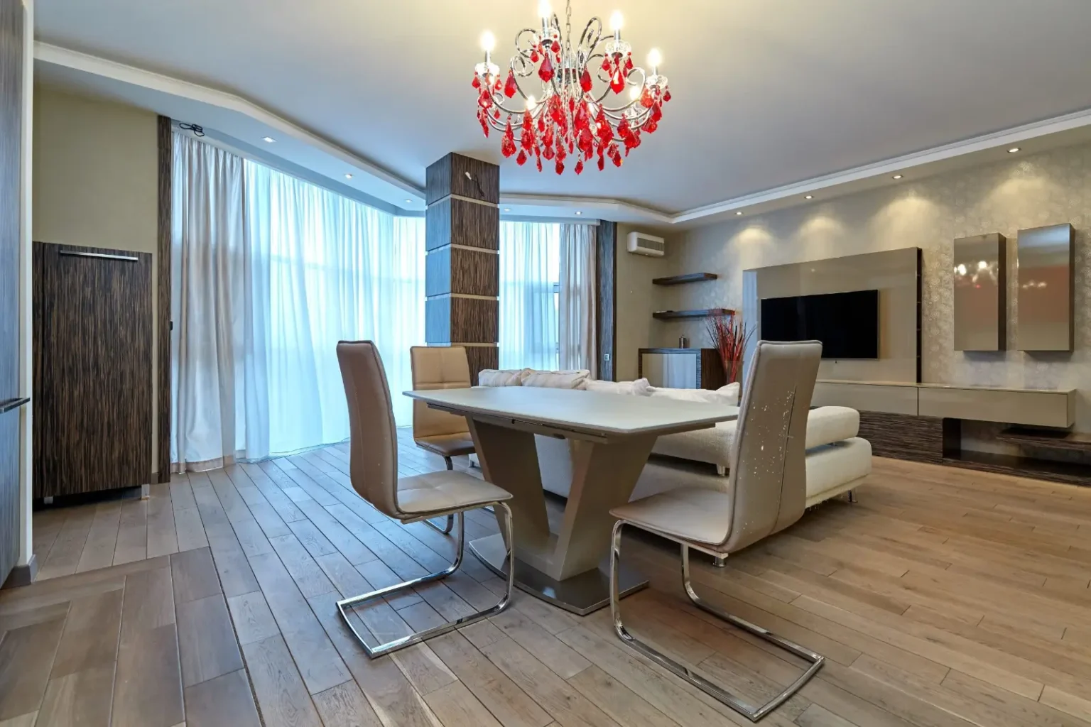 Dining room lit by a statement red crystal chandelier over an oval table
