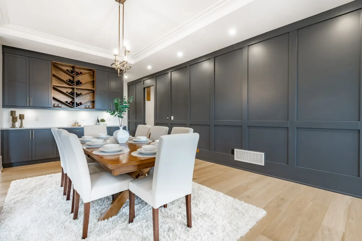 Dining room with full-height navy wall panelling and a built-in wine rack at the end