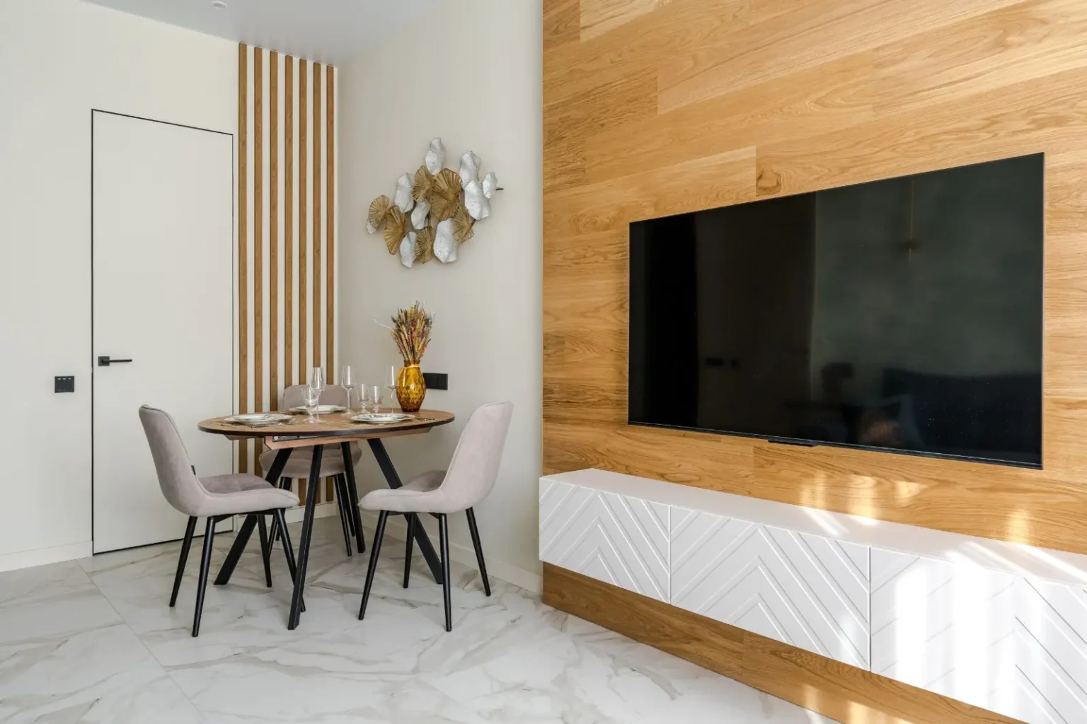 Dining nook screened by a fluted timber panel beside a herringbone feature wall