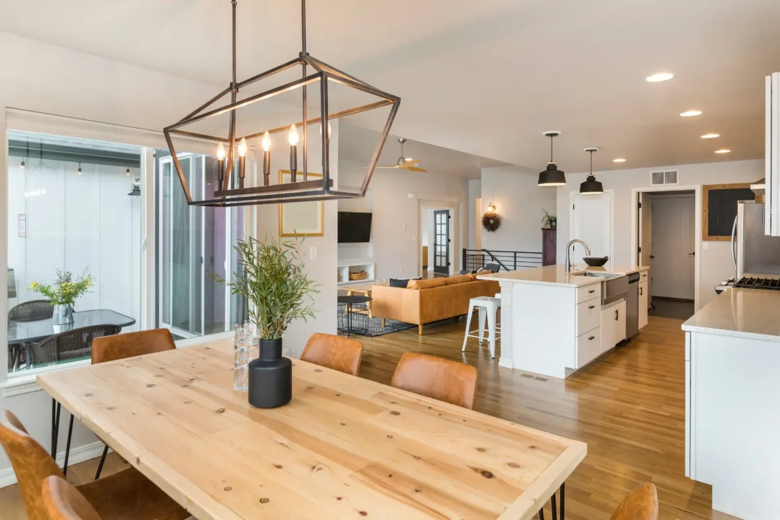 Open-plan kitchen and dining with a reclaimed timber table under a lantern pendant