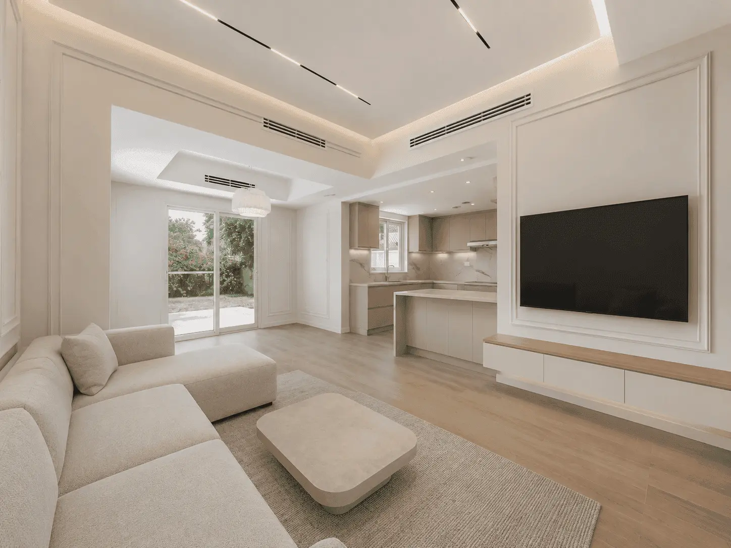 Lakes villa renovation showing a completed open-plan living room with magnetic track lighting, cove-lit gypsum ceiling, wall moulding, beige sofa, TV media wall and open kitchen with garden view by Fitout Renovation Dubai