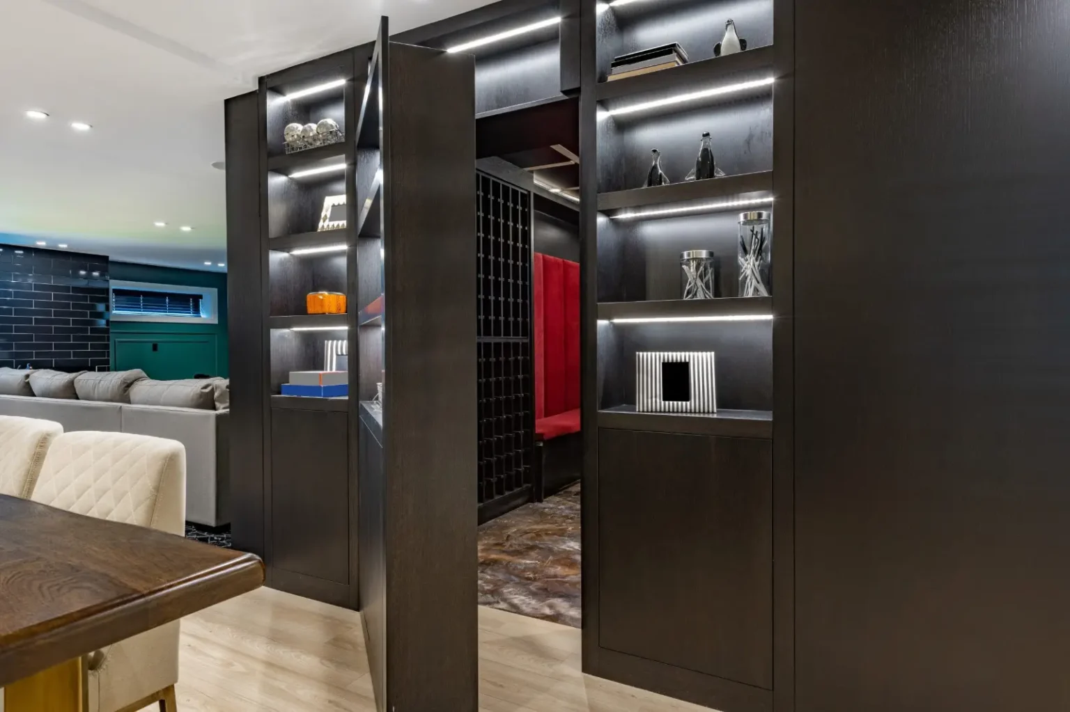 Hidden bookshelf door set into panelled wall cladding leading to a wine room in Dubai