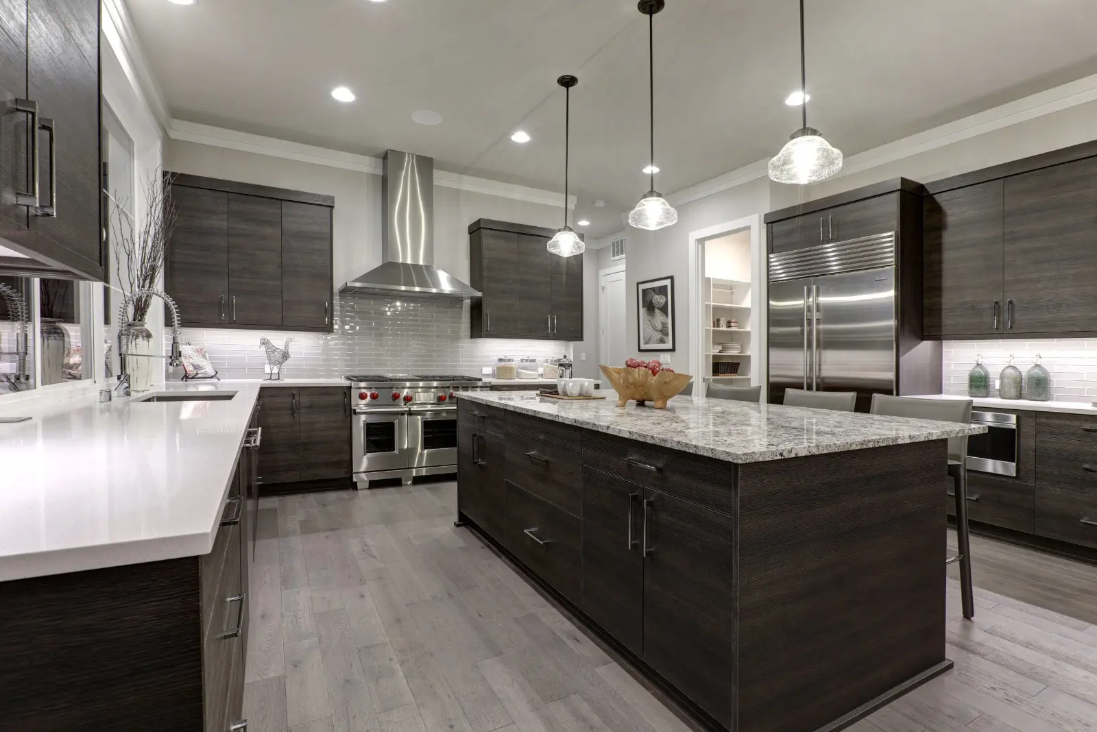 Dark wood kitchen cabinets with a granite worktop island and gas hob in a Dubai villa kitchen renovation